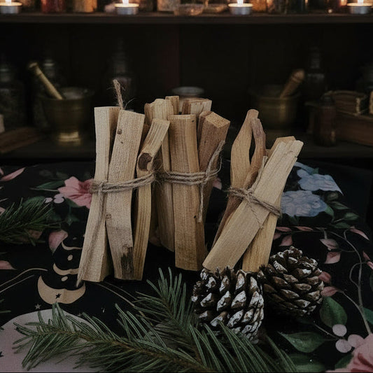Wooden bundles tied with twine on a table with a dark background featuring shelves with bottles and candles.