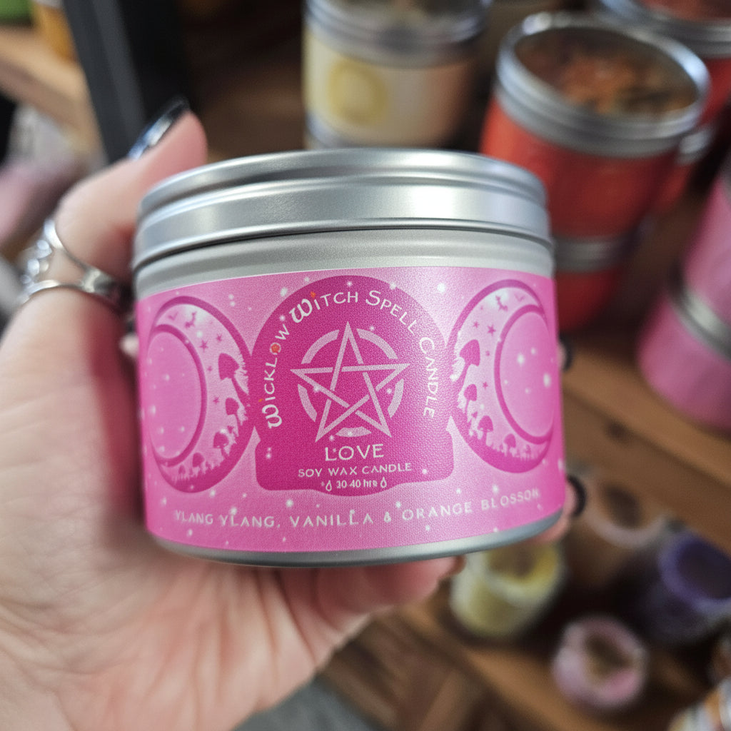 Pink candle in a tin held by a hand with a blurred store background