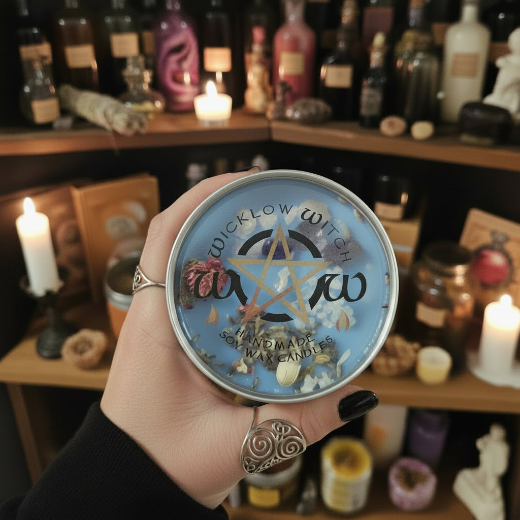 Hand holding a decorative tin with 'Wicklow Witch' branding against a background of shelves with candles and bottles.
