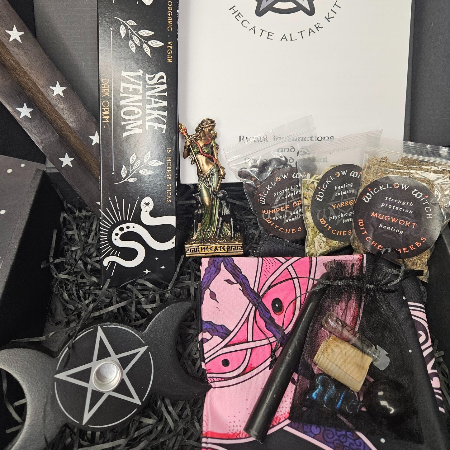 Witchy products including a snake venom kit, Hecate Altar Kit, and various witchcraft items on a dark surface.