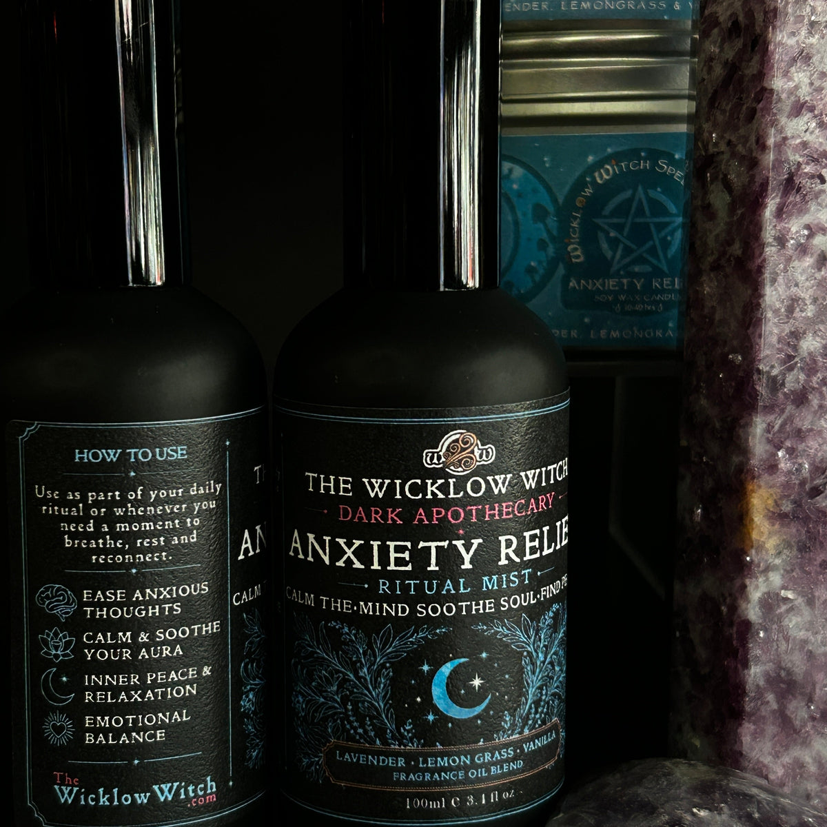 Two dark bottles of The Wicklow Witch 'Anxiety Relief' ritual mist displayed alongside a purple crystal cluster against a dark background.