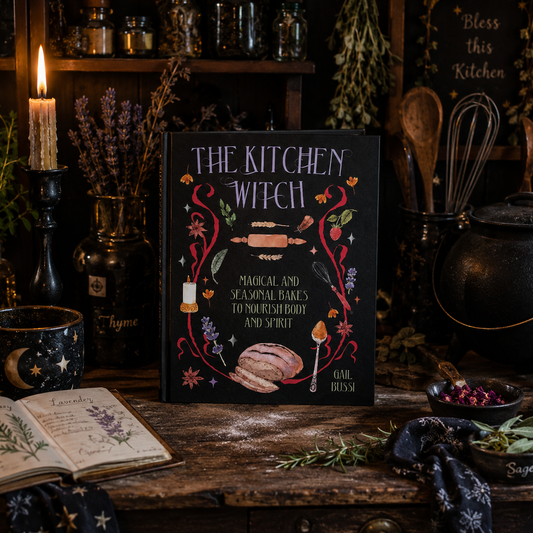 Cookbook titled 'The Kitchen Witch' on a rustic wooden table with witchcraft-themed decor.