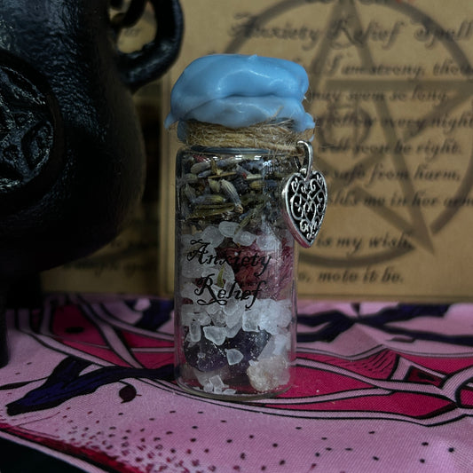 Anxiety Relief jar with lavender, salt, and blue wax seal, displayed on a pink patterned cloth with a black cauldron and parchment background.