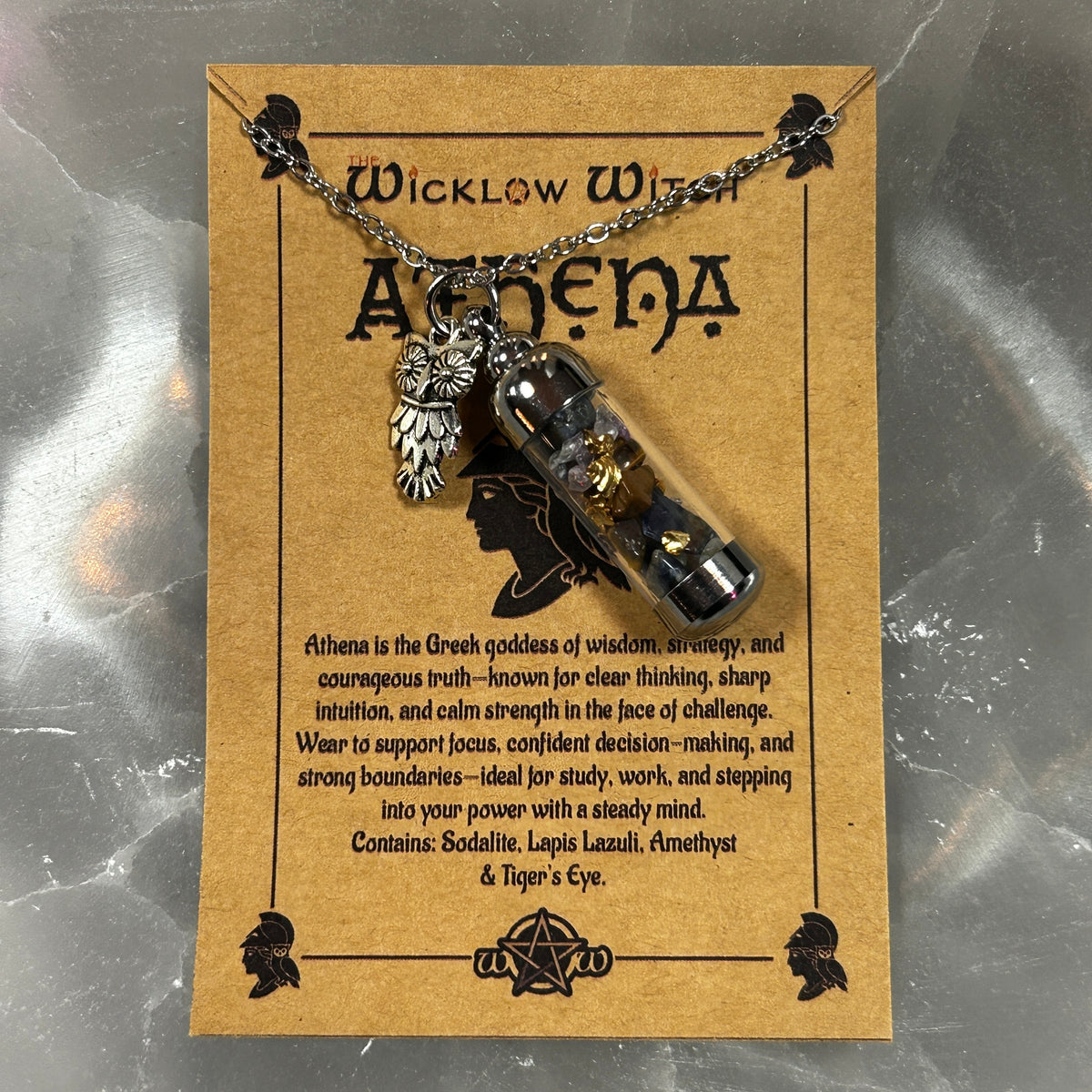 A necklace displayed on a tan card labeled 'Wicklow Witch Athena.' The necklace has a silver-toned chain and owl pendant, with a clear glass vial.