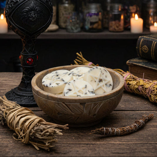 Witchcraft altar with candles, books, and herbs on a wooden surface.